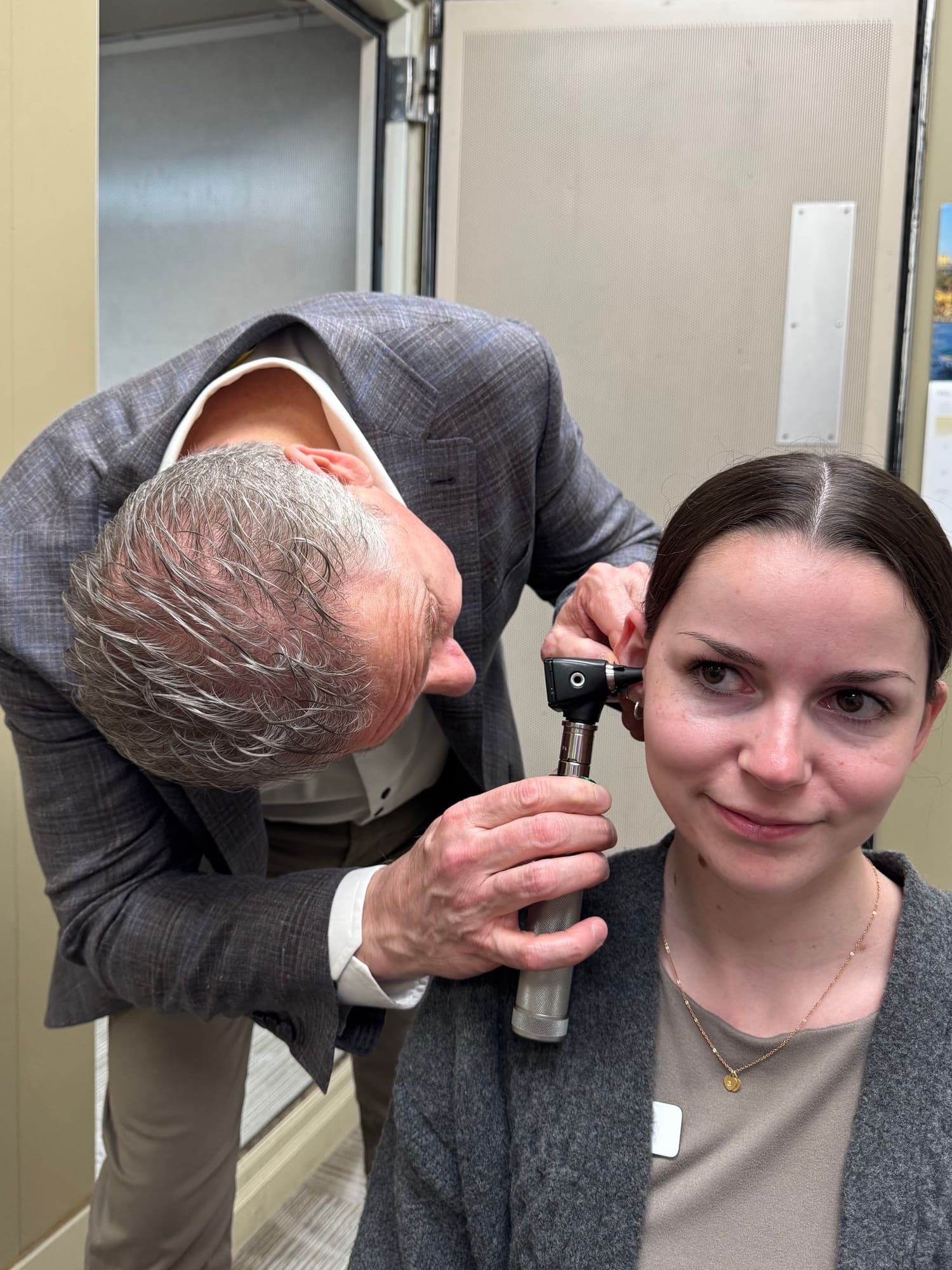 An audiologist or hearing instrument specialist examining a patient's ear with an otoscope at Sense of Hearing Burlington
