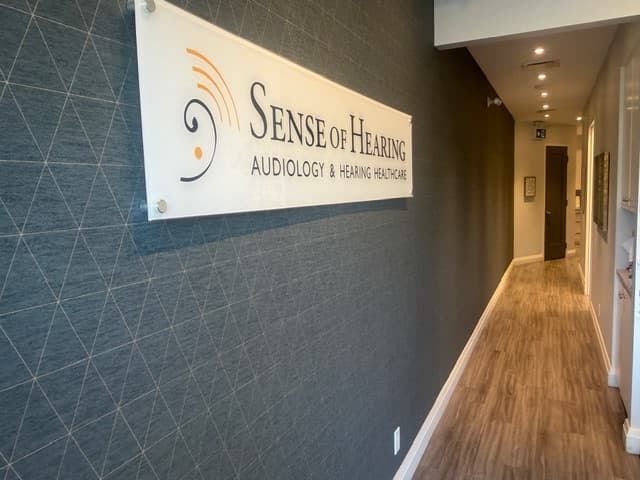 Hallway at Sense of Hearing Etobicoke with the clinic logo sign mounted on a textured accent wall