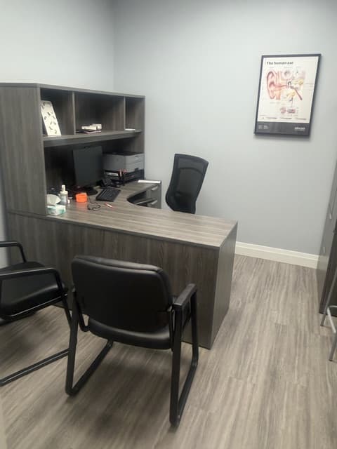 Consultation office at Sense of Hearing Etobicoke with a desk, seating, and an anatomical diagram of the human ear
