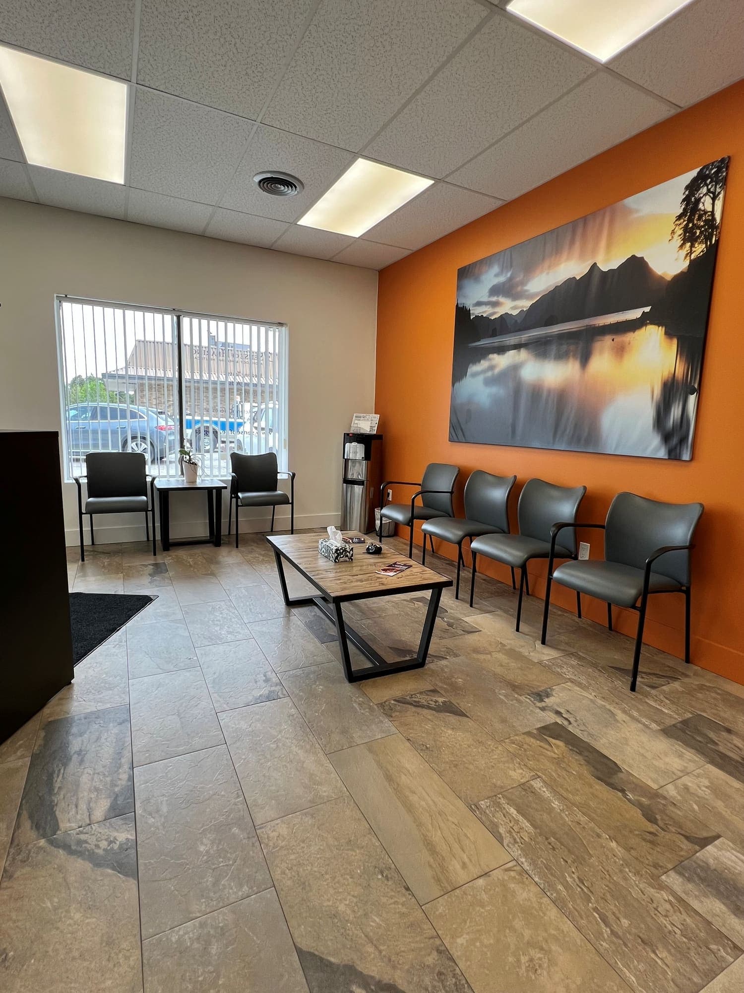 Waiting area at Sense of Hearing Waterdown with seating beneath a framed mountain-lake landscape print