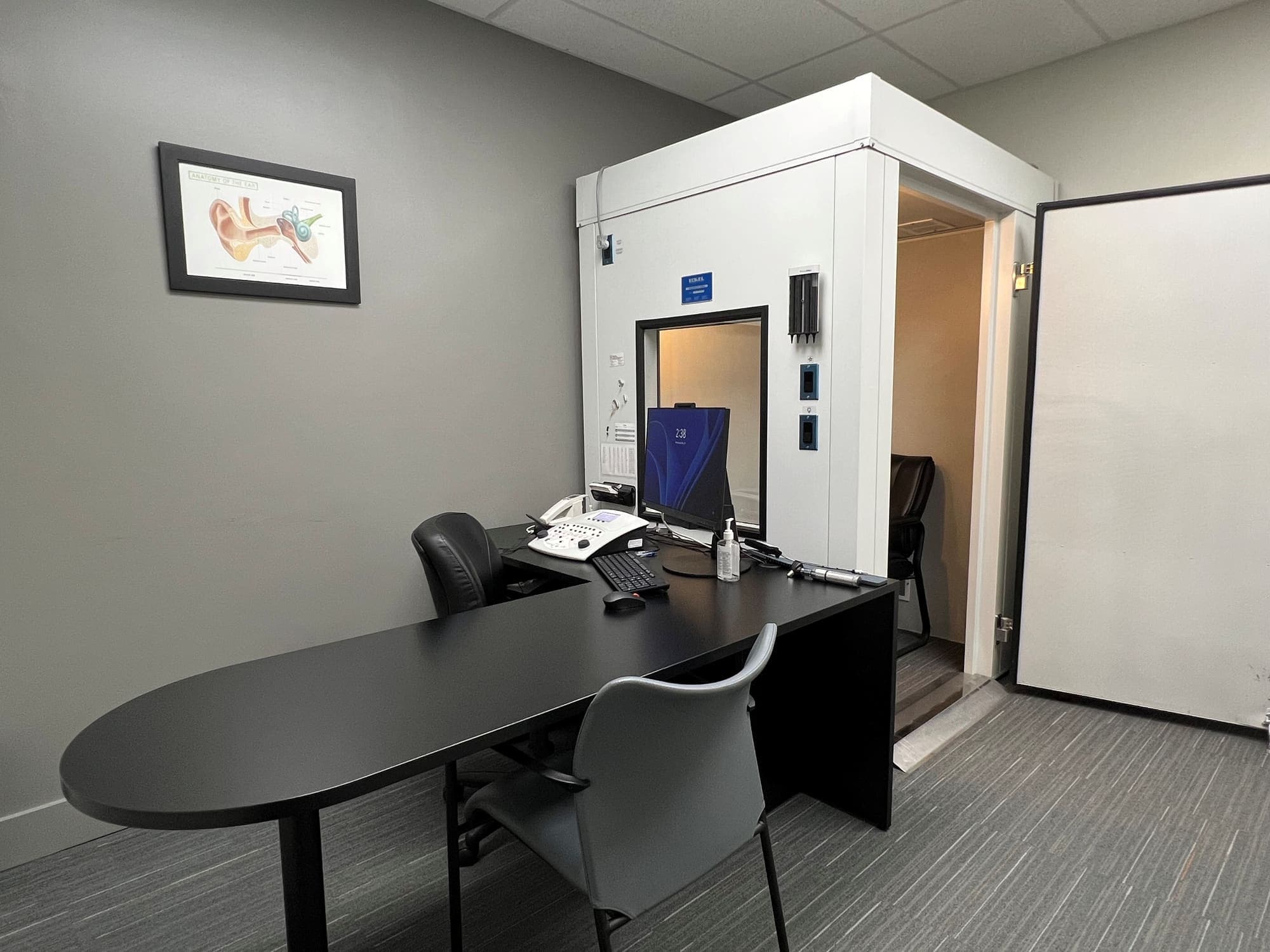 Hearing assessment room with sound booth and an anatomy-of-the-ear chart at Sense of Hearing Waterdown